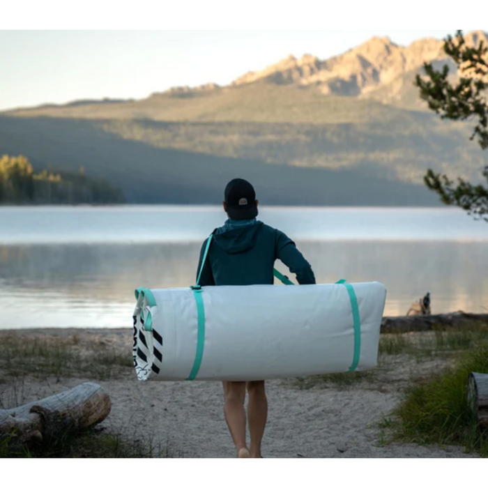 Guy carrying a deflated POP Board Co. POPUP Dock 8x7 down a sandy path.