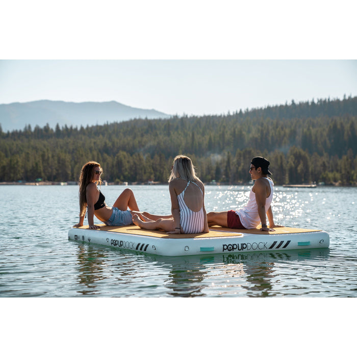 Two girls and a guy relaxing on the POPUP Dock in the middle of a lake.