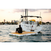 Guy sitting on a POP Dock tied up behind a sailboard out in the middle of a bay.