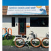 Priority Bicycles E-Coast white step-thru ebike in front of Current Riders Fort Myers Beach. 