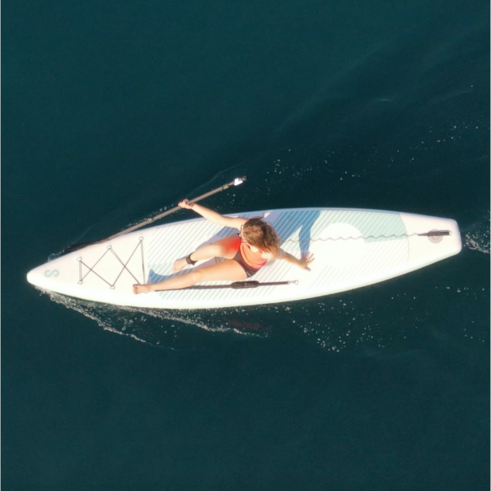 Female paddler sitting on SipaBoards Drive Tourer Aqua iSUP with a paddle on the water.