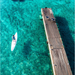 Man on SipaBoards Allrounder Aqua eSUP in clear water next to pier.