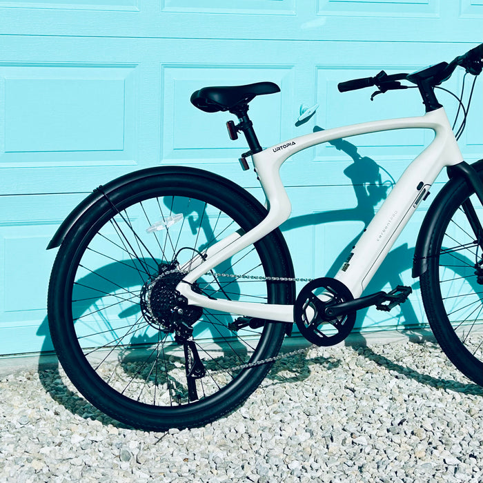 Urtopia Carbon 1 Pro eBike back tire against a light blue wall.