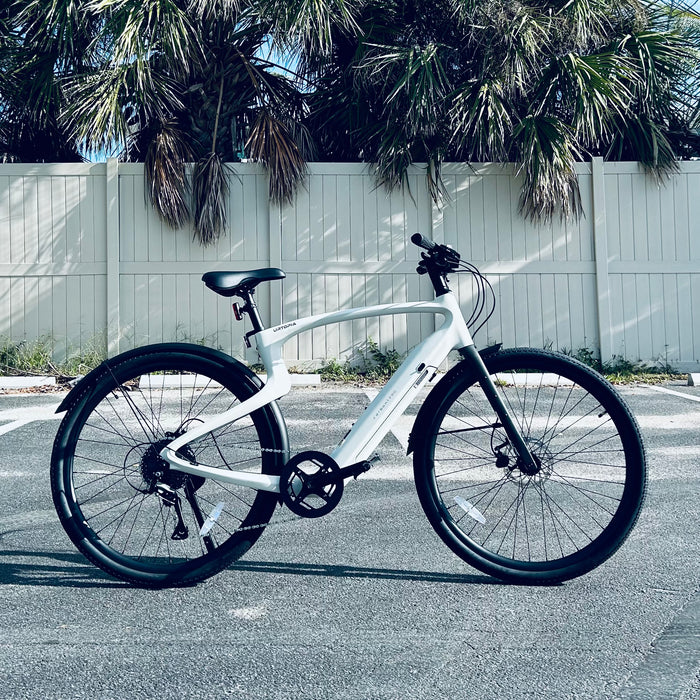 Urtopia Carbon 1 Pro eBike in a parking lot with a white fence and palm trees in the background.