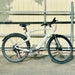 Urtopia Carbon 1 Pro eBike parked on a sidewalk with a tan gate in the background.