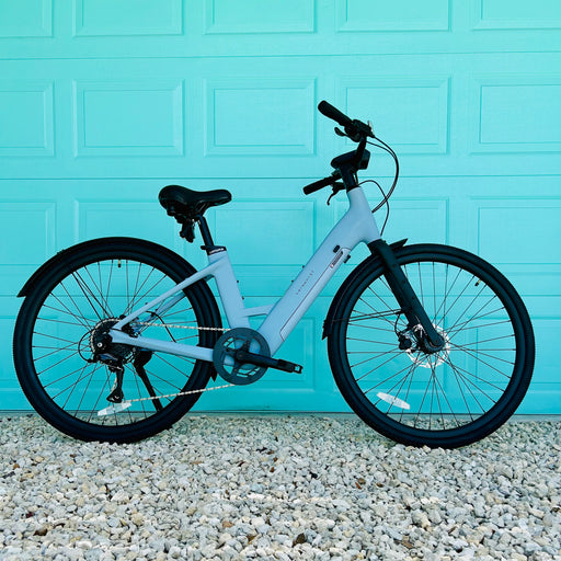 Urtopia Carbon ST Glacier Blue ebike parked in front of aqua colored door. 