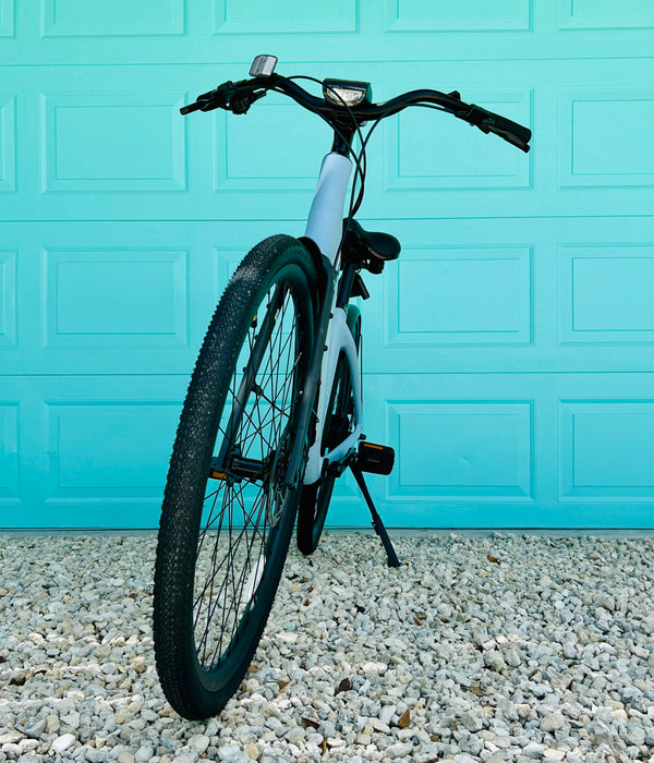 Front view of the Urtopia Carbon ST Glacier Blue ebike parked in front of aqua colored door. 