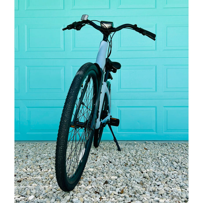 Front view of the Urtopia Carbon ST Glacier Blue ebike parked in front of aqua colored door. 