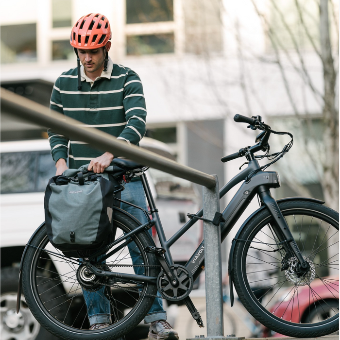 Guy securing bag to Vvolt Alpha II Electric Bike in the city.