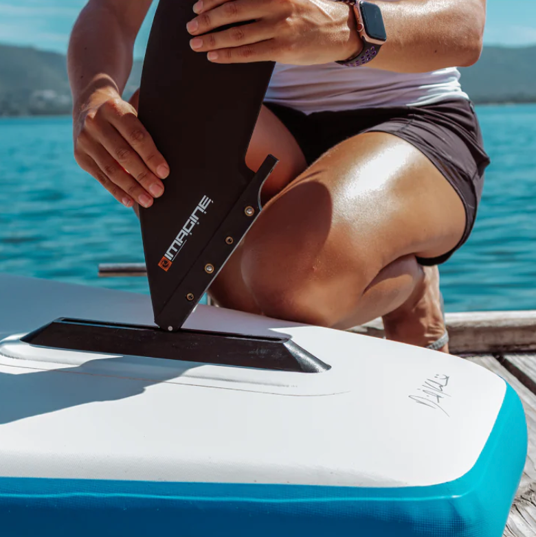 Woman placing the fin on a Imagine Surf Mission iSUP.