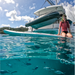 Woman with snorkel gear on sitting on SipaBoards Allrounder Motorized SUP on the water with fish under the board.
